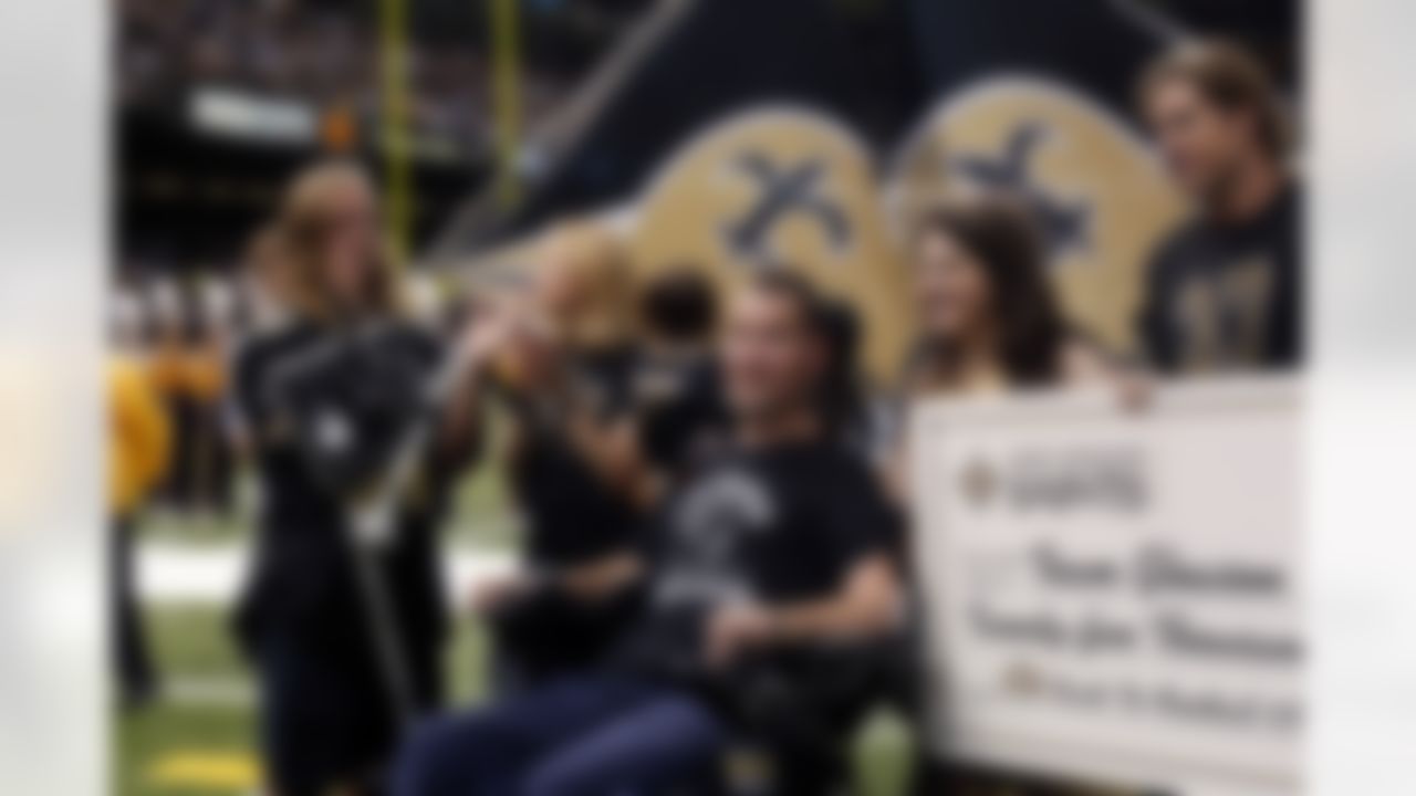 Former New Orleans Saints Steve Gleason, who suffers from ALS, is presented a check by Rita Benson LeBlanc, second right, before an NFL football game against the Atlanta Falcons in New Orleans, Sunday, Sept. 8, 2013. (AP Photo/Bill Haber)