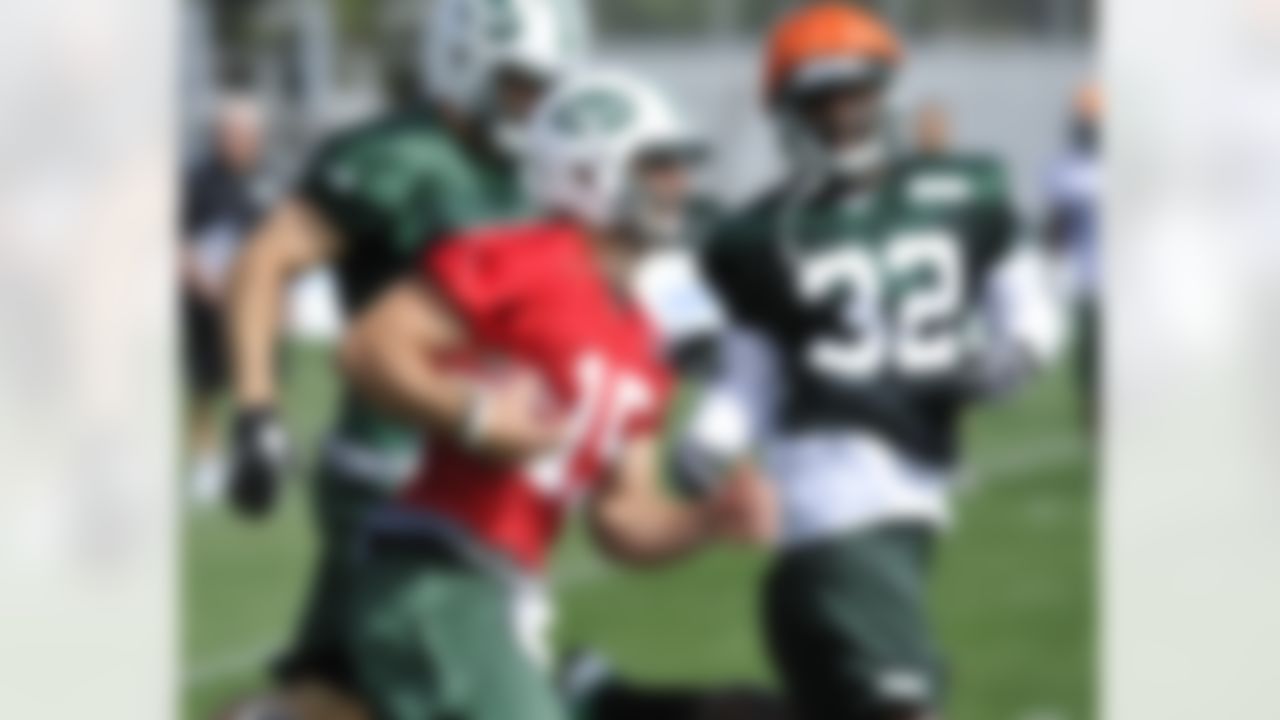 New York Jets quarterback Tim Tebow runs with the ball as safety Josh Bush (32) closes in on opening day of their NFL football training camp Friday, July 27, 2012, in Cortland, N.Y. (AP Photo/Bill Kostroun)