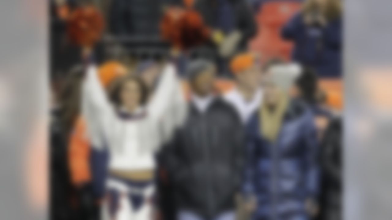 Tiger Woods, center, and Lindsey Vonn, right, watch from the sidelines as the Denver Broncos and the Kansas City Chiefs warm up before an NFL football game, Sunday, Nov. 17, 2013, in Denver. (AP Photo/Joe Mahoney)