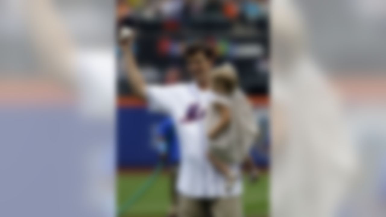 New York Giants quarterback Eli Manning holds the ball and his daughter Ava before throwing out the first pitch before the New York Mets play the Cincinnati Reds at Citi Field in New York on June 17, 2012. (AP Photo/Kathy Willens)