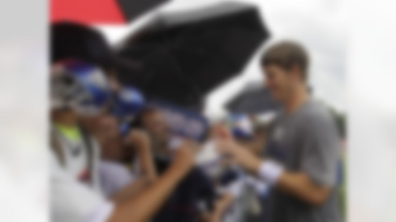 Fans gather around New York Giants quarterback and two-time Super Bowl MVP Eli Manning as he signs autographs during autograph day at the New York Giants NFL football training camp in Albany, N.Y., Saturday, July 28, 2012. (AP Photo/Kathy Willens)