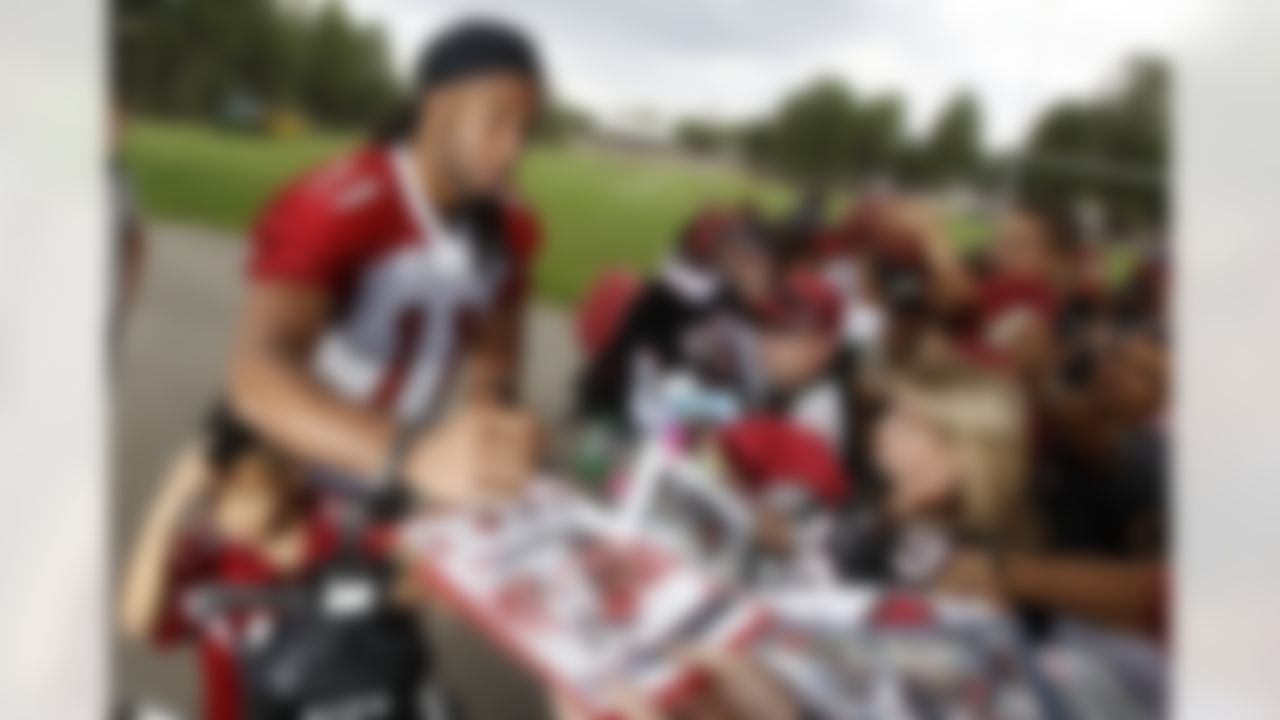 Arizona Cardinals' Larry Fitzgerald (11) signs autographs for fans as his son, Devin Fitzgerald, waits after the first day of NFL football training camp at Northern Arizona University, Wednesday, July 25, 2012, in Flagstaff, Ariz. (AP Photo/Ross D. Franklin)