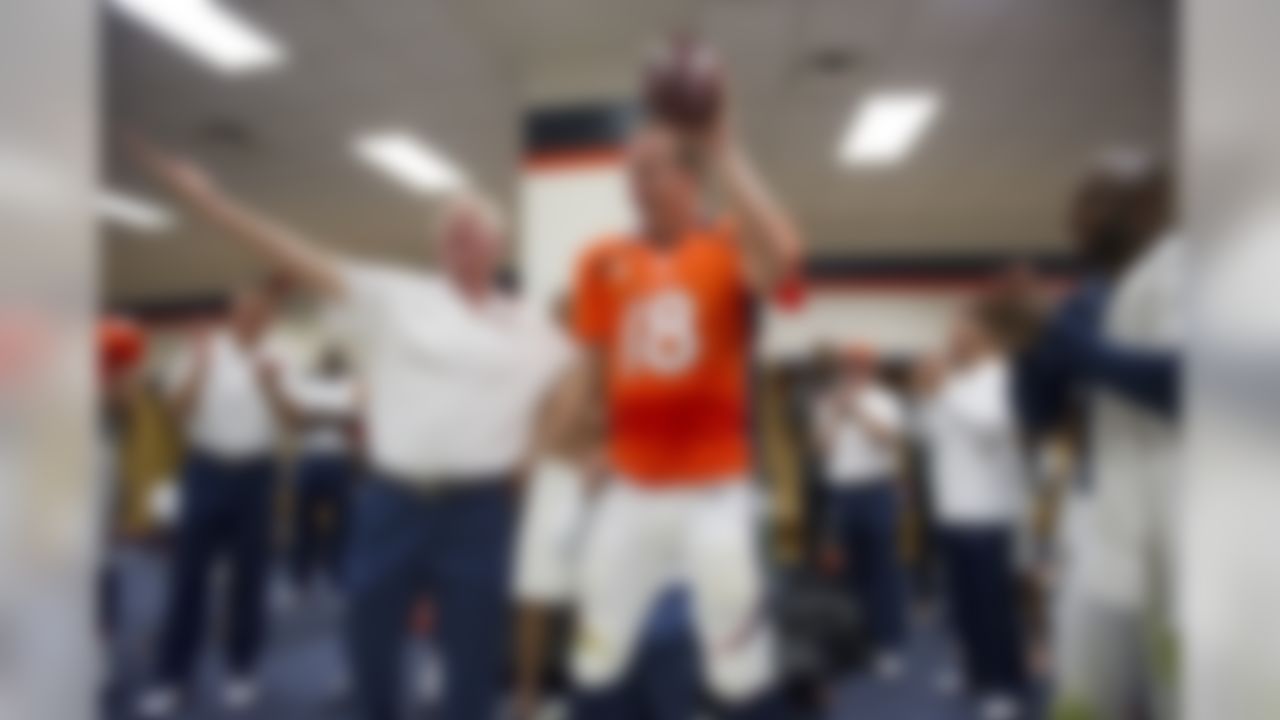Denver Broncos Head Coach John Fox and the squad cheer Peyton Manning (18) after Fox presented Manning with a game ball in the locker room for Manning's 400th and 401st touchdown passes in his career and first game as a Broncos quarterback at Sports Authority Field in Denver, CO. September 9, 2012. (AP Photo/ Eric Bakke )