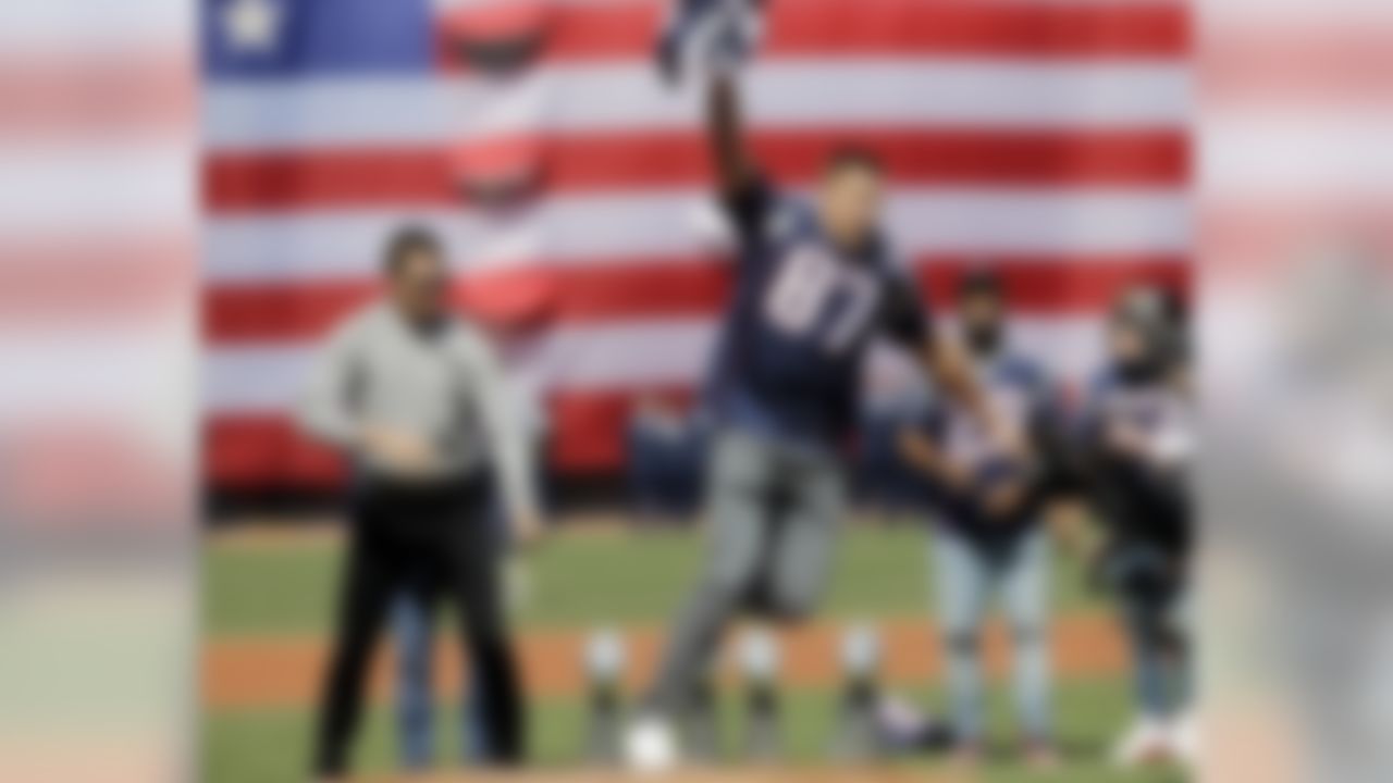 New England Patriots tight end Rob Gronkowski (87) runs with quarterback Tom Brady's, far left, recovered Super Bowl jersey as they joke around during Boston Red Sox home opening day ceremonies at Fenway Park, Monday, April 3, 2017, in Boston. The Red Sox face the Pittsburgh Pirates in the baseball game. (AP Photo/Elise Amendola)