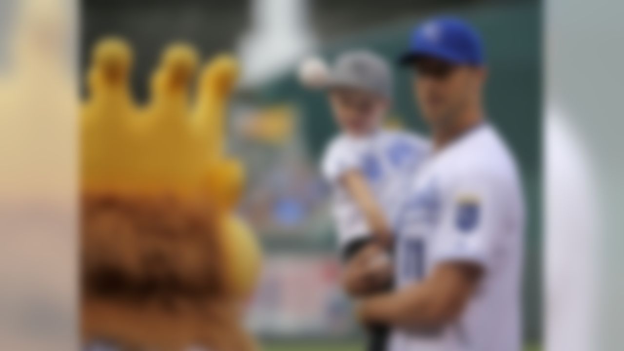 Kansas City Chiefs quarterback Alex Smith, holding his son Hudson, age 3, throws out the first pitch before a baseball game between the Kansas City Royals and the New York Yankees Friday, June 6, 2014, in Kansas City, Mo. (AP Photo/Charlie Riedel)