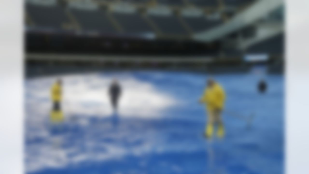 Stadium employees push rain water off the tarp at Soldier Field before an NFL football game between the Chicago Bears and Minnesota Vikings, Sunday, Sept. 15, 2013, in Chicago. (AP Photo/Charles Rex Arbogast)