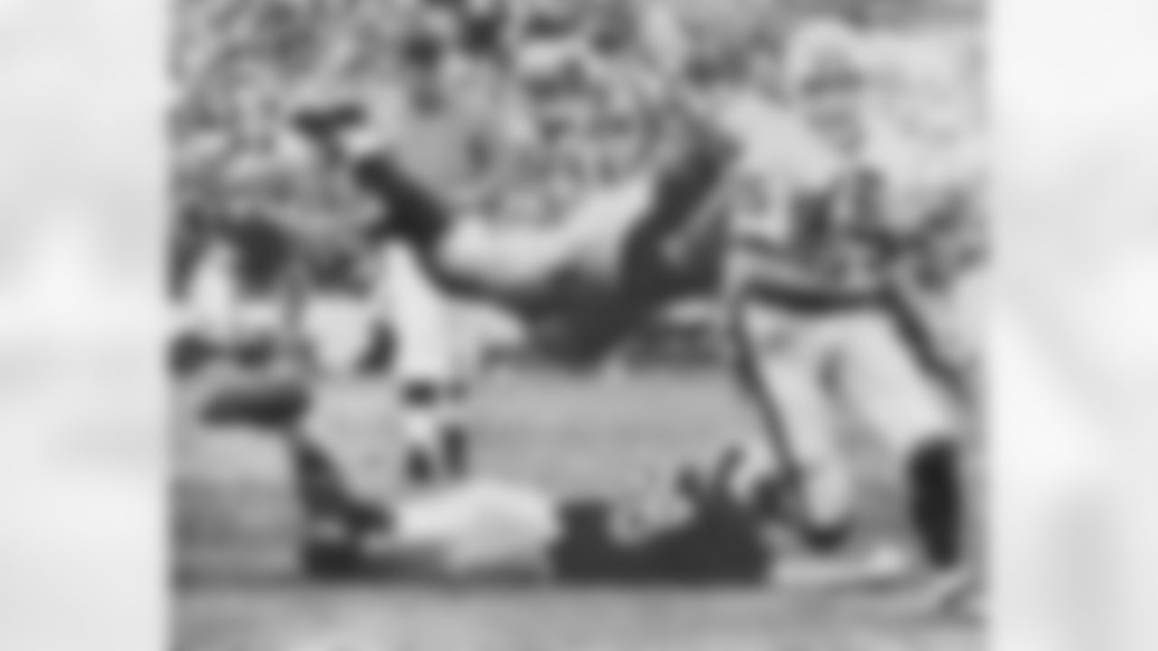An flying Illinois tackler hits the head of Wisconsin quarterback Ron Vanderkelen (15) and another Illinois man grabs him by the feet as they try to stop him as he runs for a first down in the second quarter, Nov. 17, 1962, Champaign, Ill. Illinois center Dick Butkus is the flying tackler and Illinois and Rich Callaghan is the ground man. (AP Photo/Larry Stoddard)