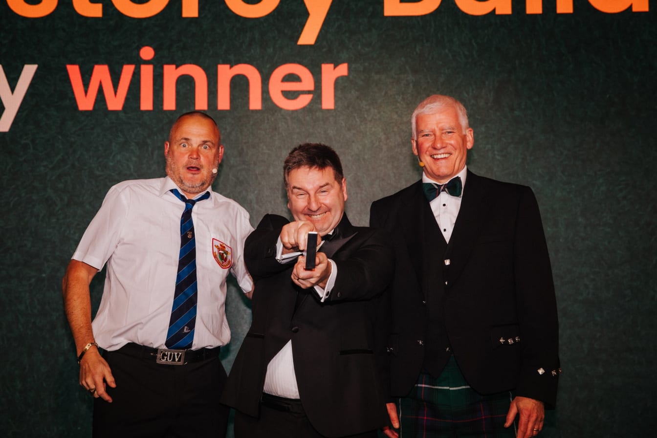 Pride in the Job 2024 Award winner Stephen Harnett on stage with host Al Murray and NHBC CEO Steve Wood