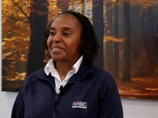 a woman in a black jacket looking off camera and smiling