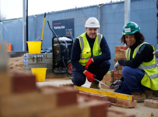 A tutor and bricklaying apprentice smiling at the camera