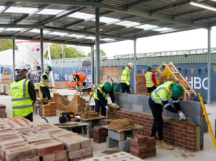 an action shot of apprentices at nhbc's cambridge training hub building a brick wall