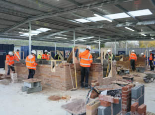 a group of people wearing safety clothes and building brick walls at NHBC training hub