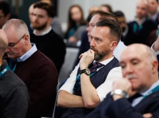 a man in the audience listening to a presentation at an event