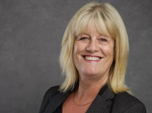 Alison smiling at the camera with a grey background