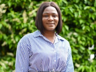 Kelechi looking at the camera in a blue stripped shirt