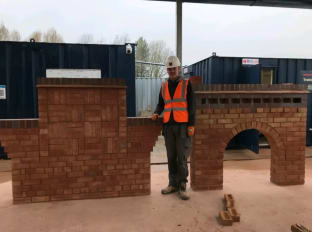 a man wearing safety clothes standing next to a brick wall