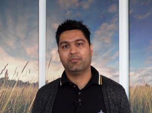 a man in a black shirt smiling at the camera