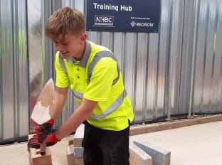 a young boy wearing safety clothes and laying bricks at NHBC Training Hub