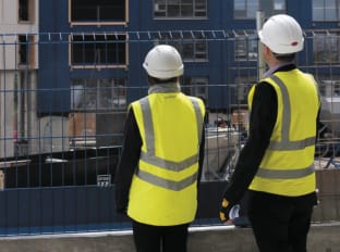 a photo of two people on site wearing site safety clothing