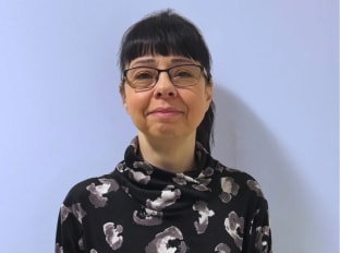 Debbie Williams looking at the camera on a purple background