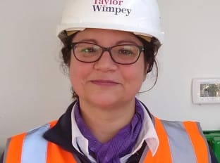 Laura Gravener smiling at the camera in high vis safety clothing and hard hat