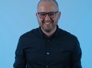 Ryan smiling at the camera on a blue background