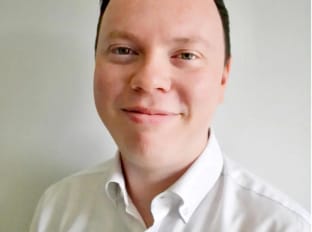 a man in a white shirt smiling at the camera