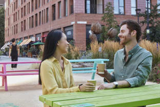 Two people drinking a coffee on a picnic bench