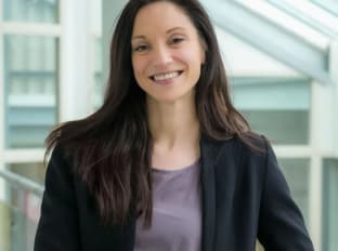 a photo of a brunette woman called hazel in a smart outfit smiling at the camera