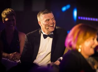 a man in a suit at the nhbc pij supreme awards smiling