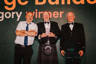 David holding an awards and smiling at the camera