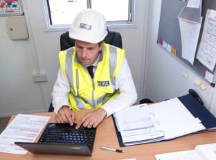 a person in a high vis vest an hard hat signing a document