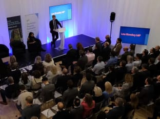 a presenter talking on stage with an audience