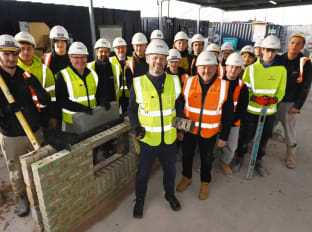 the bricklaying apprentice team with the North of Tyne Mayor in site safety clothing smiling at the camera