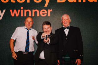 Pride in the Job 2024 Award winner Stephen Harnett on stage with host Al Murray and NHBC CEO Steve Wood