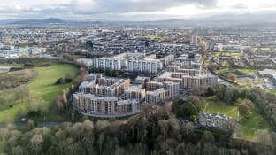a drone shot of high-rise buildings and green fields