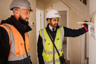 Two men in ppe inspection a consumer unit