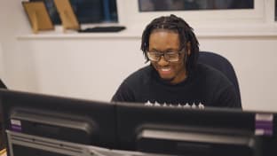 Kelly Enyo Banini's smiling at his desk