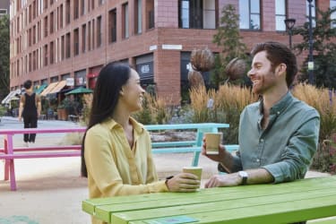 Two people drinking a coffee on a picnic bench