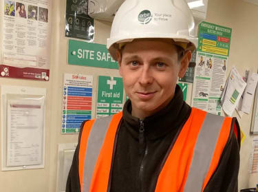 a man in hi-vis top and a helmet smiling in front of a camera