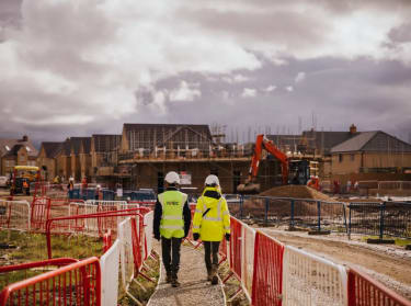 two people in high vis safety clothing walking on a new build site