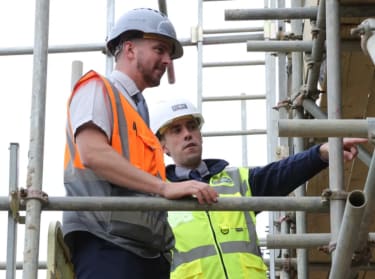 two men on a construction site wearing safety clothes