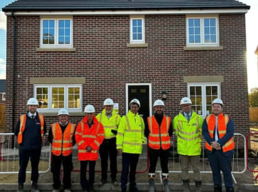 people in high vis safety clothing smiling at the camera on a new build site