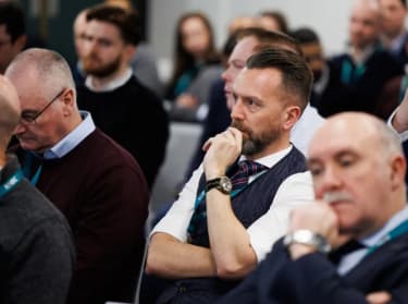 a man in the audience listening to a presentation at an event