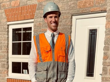 a man in hi-vis and helmet standing in front of a house
