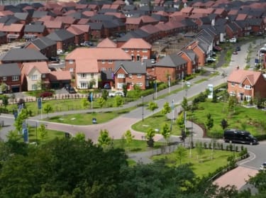 a drone shot of a new build development with red brick houses and green areas