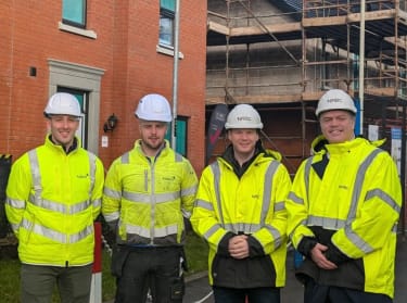four men in high vis safety clothing smiling at the camera
