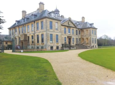 a photo of belton house from the outside, showing a beige manor house and large, sprawling gardens