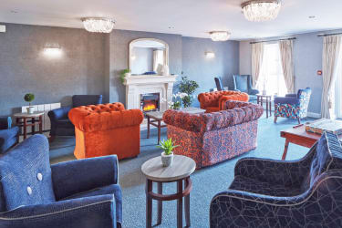 a photo of a lounge with orange sofas and arm chairs