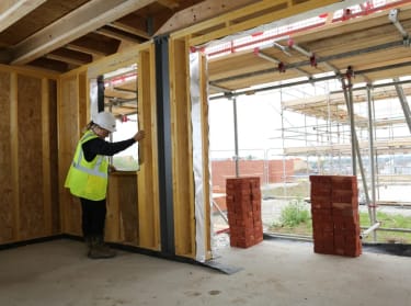 woman in high vis safety clothing inspecting a timber frame